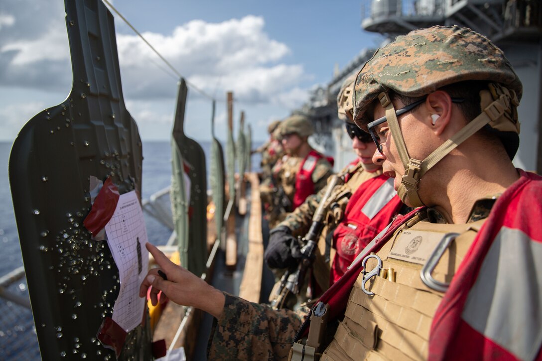 Marines assess shooting practice targets aboard a military ship.