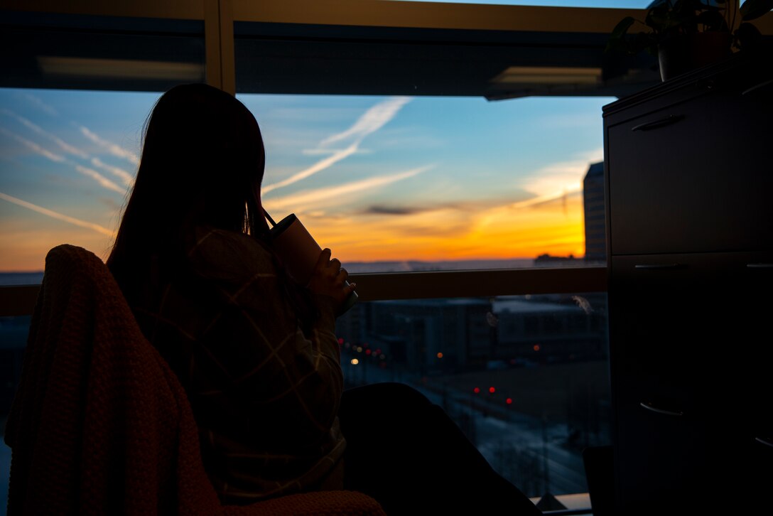 A member of the administration staff at the U.S. Army Corps of Engineers Omaha District watches the sunrise from the headquarters building in Omaha, Neb.