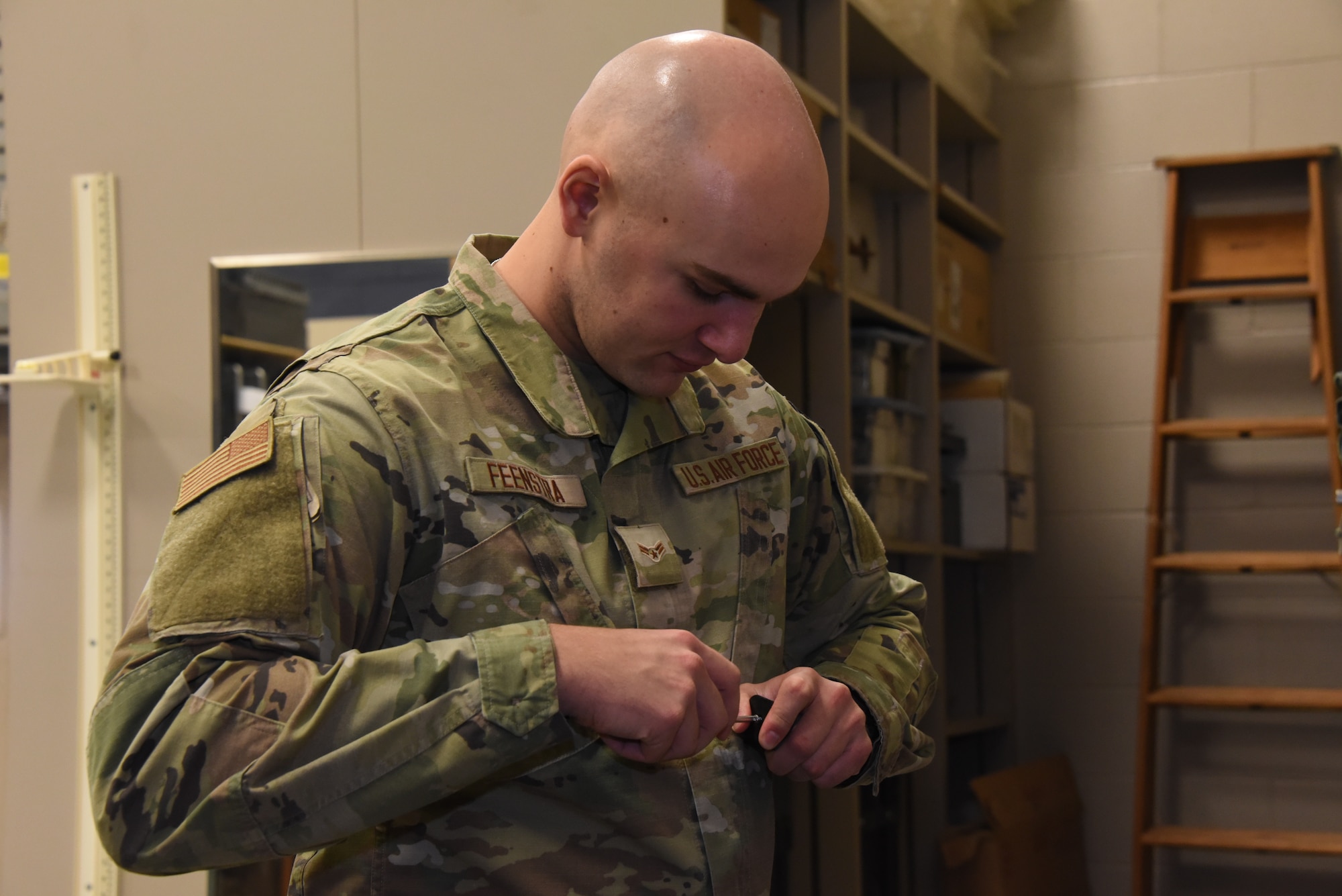 Airman performs maintenance on battery compartment of device