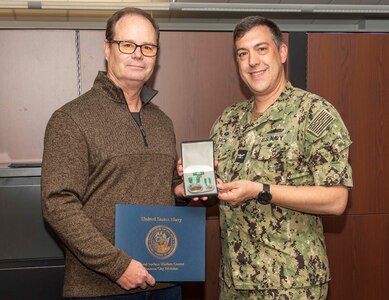 (right) Naval Surface Warfare Center Panama City Division Command Officer Capt. David Back, presents the Navy Civilian Service Commendation Medal to Vincent Tomasi, NSWC PCD contracts officer, Dec. 14. Tomasi, who has been affiliated with the military for nearly 40 years, has provided his contracting expertise to NSWC PCD for the last seven years. (U.S. Navy Photo by Eddie Green)