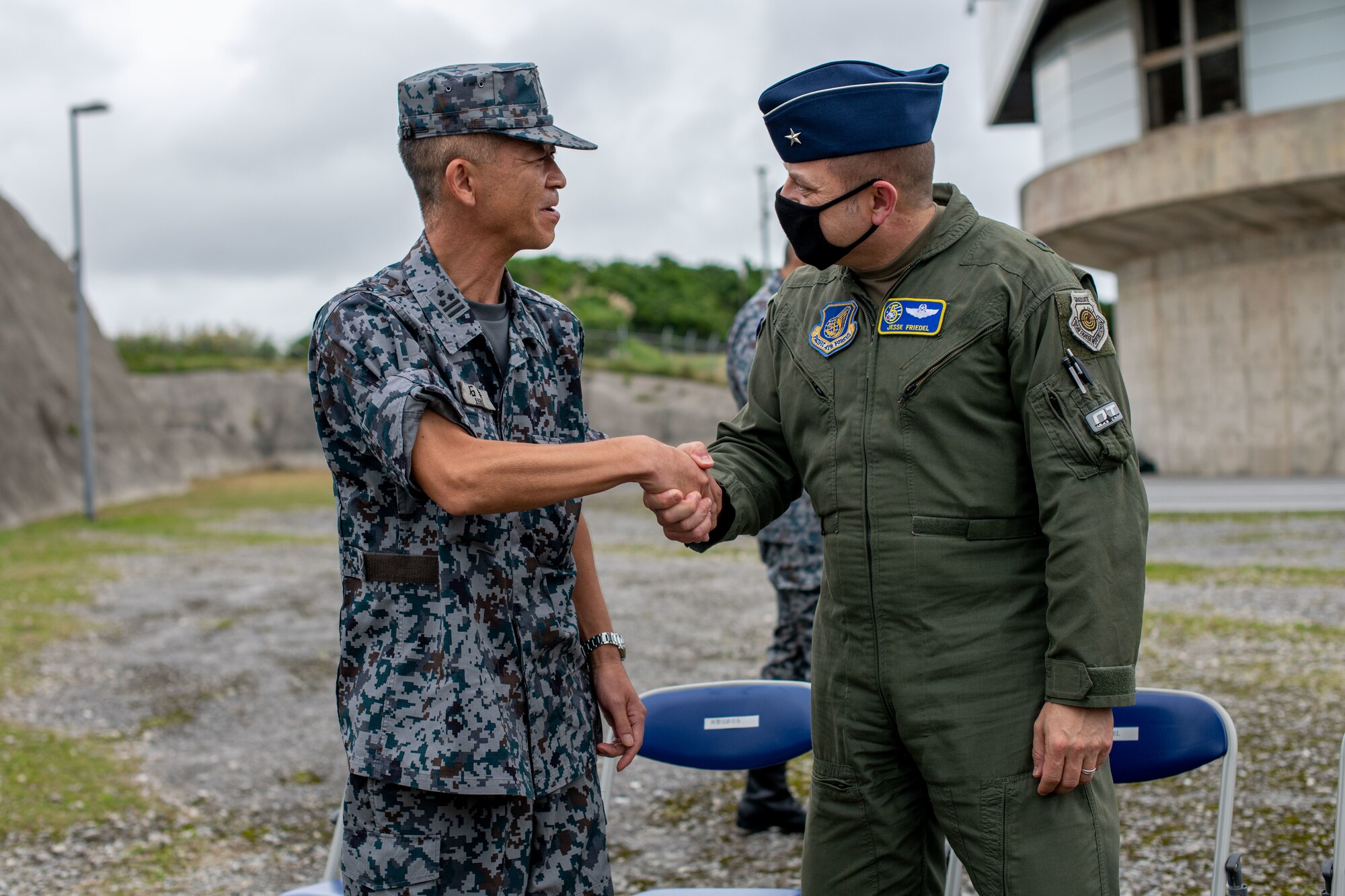 An Airman and Japanese service member shake hands.