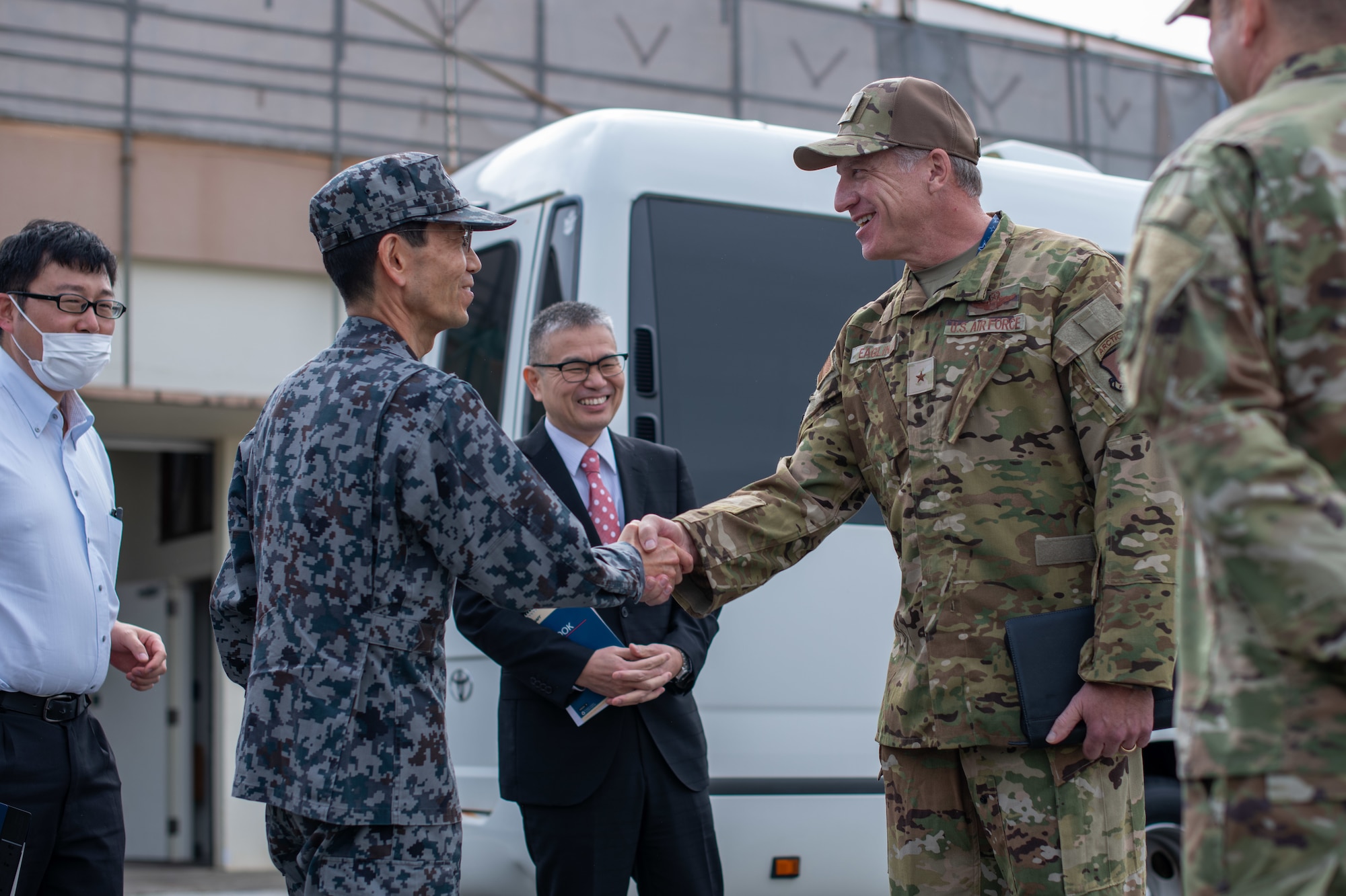 An Airman and Japanese service member shake hands.