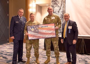 (From left) Commander of Air Mobility Command Gen. Mike Minihan, commander of the 60th Air Mobility Wing, Col. Derek M. Salmi, and Deputy Assistant Secretary of Air Force Operational Energy, Roberto Guerrero, pose for a photo after the Mission Execution Excellence Program award ceremony at the Airlift Tanker Association Symposium on October 26, 2022, in Denver, Colorado. (Airlift Tanker Association photo)