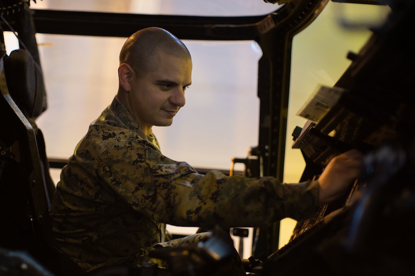 A Marine makes adjustments on aircraft dashboard.