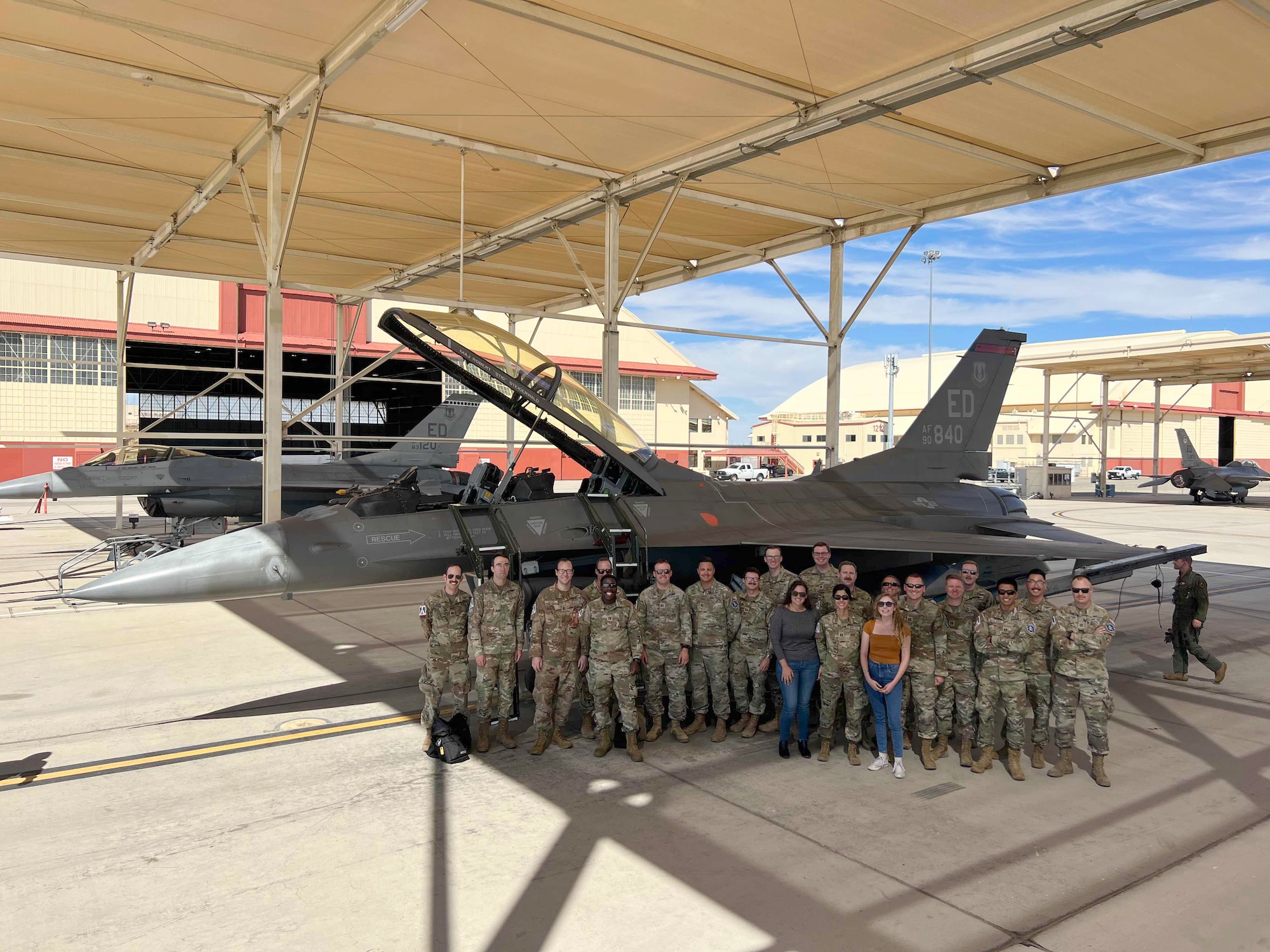 Savannah Langer, pictured front right, Arnold Engineering Development Complex aerospace engineer, stands with a large group of people by an F-16 Fighting Falcon.