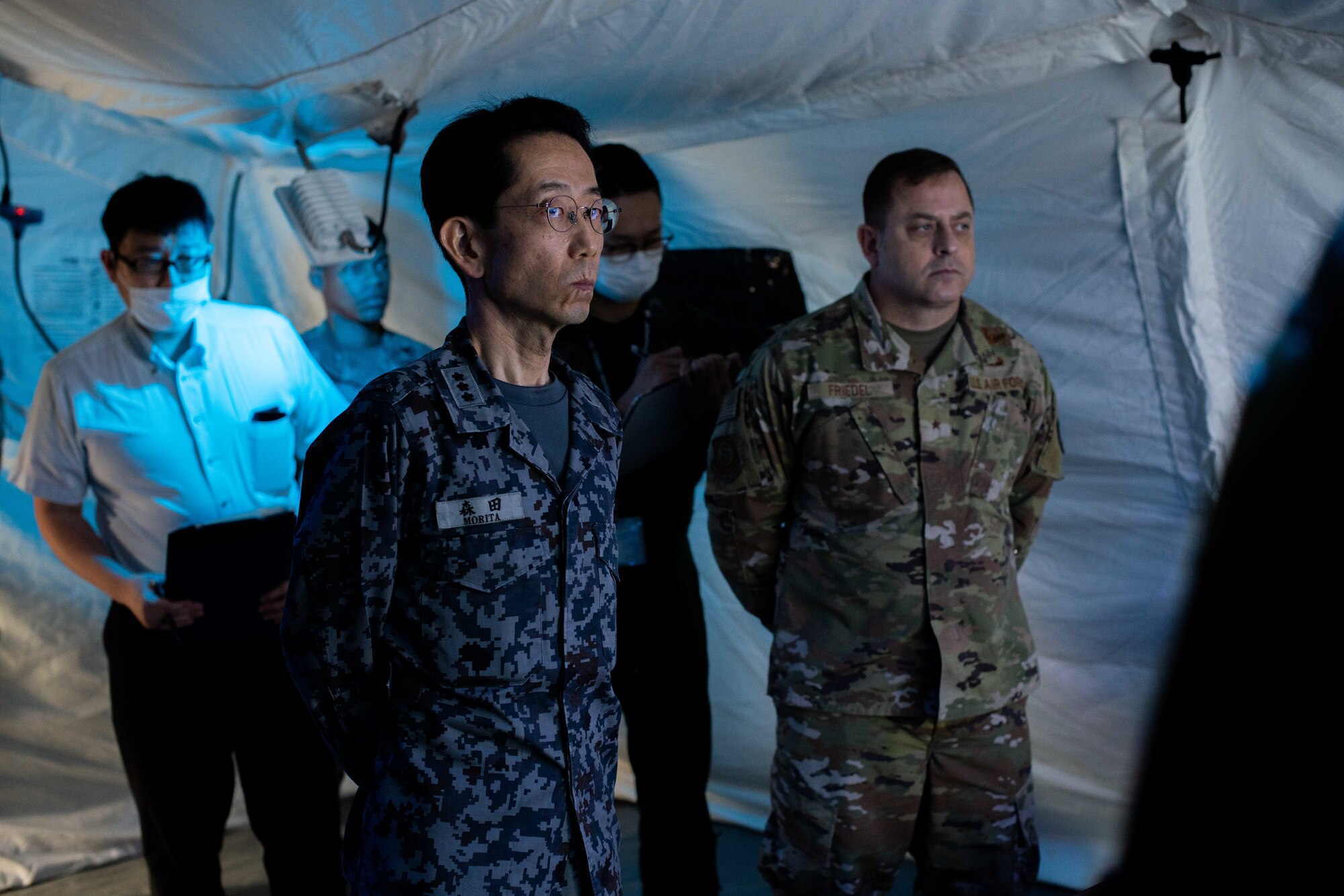 A Japanese service member and Airmen listen to a brief.