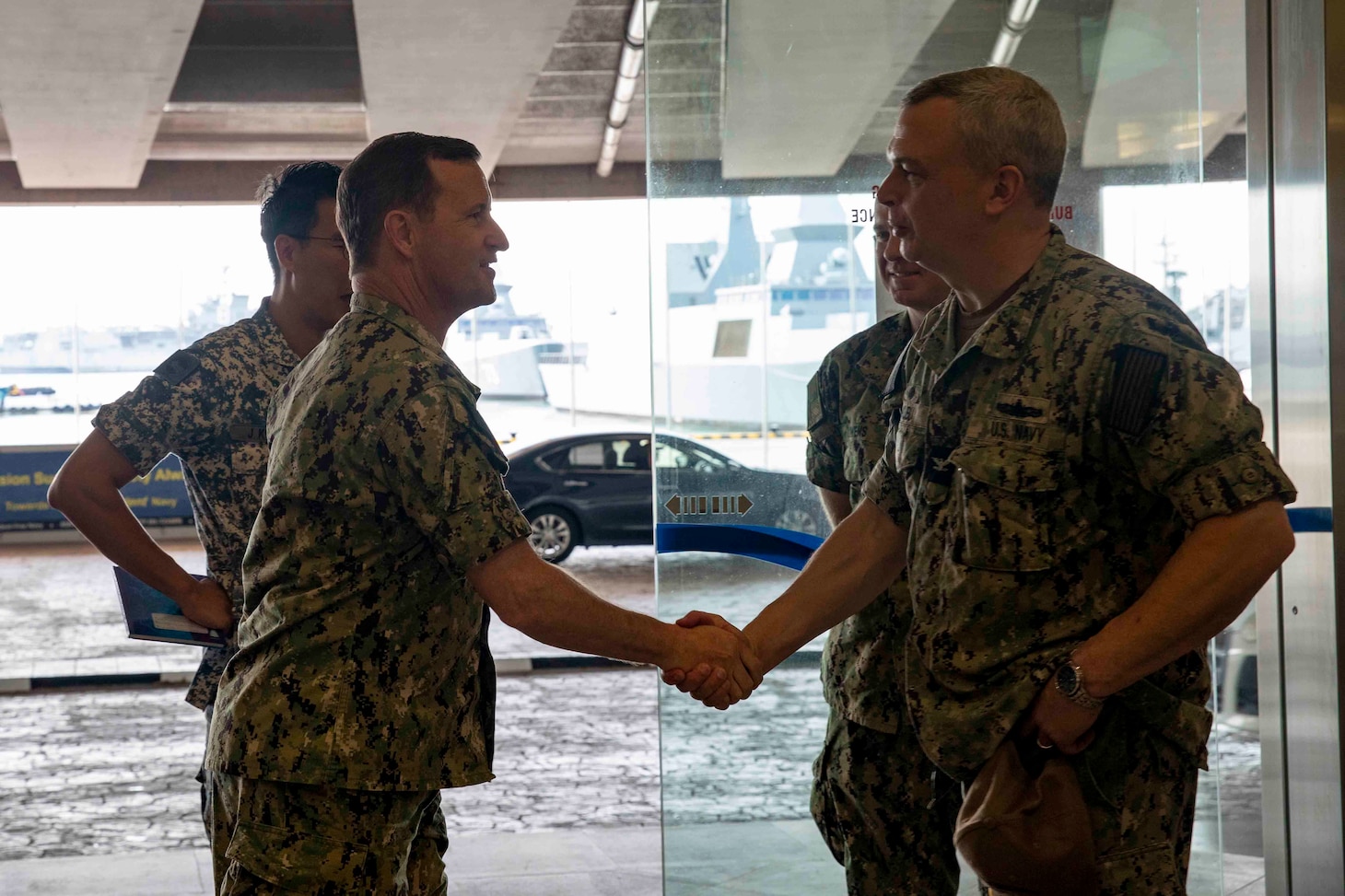 SINGAPORE (Jan. 9, 2023) Rear Adm. Mark Melson, Commander, Logistics Group Western Pacific/Task Force 73, and Capt. Justin Kubu, commodore of Amphibious Squadron SEVEN, shake hands during the opening ceremony of Cooperation Afloat Readiness and Training (CARAT)/Marine Exercise (MAREX) Singapore 2022, Jan. 9, 2023. CARAT Singapore is a bilateral exercise between Singapore and the United States designed to promote regional security cooperation, maintain and strengthen maritime partnerships, and enhance maritime cooperation. In its 28th, the CARAT series is comprised of multinational exercises, designed to enhance U.S. and partner forces’ abilities to operate together in response to traditional and non-traditional maritime security challenges in the Indo-Pacific region. The Makin Island Amphibious Ready Group, comprised of amphibious assault ship USS Makin Island (LHD 8) and amphibious transport dock USS Anchorage (LPD 23) and USS John P. Murtha (LPD 26), is operating in the U.S. 7th Fleet area of operations with the embarked 13th Marine Expeditionary Unit to enhance interoperability with Allies and partners and serve as a ready-response force to defend peace and maintain stability in the Indo-Pacific region. (U.S. Navy photo by Mass Communication Specialist 3rd Class Kendra Helmbrecht)