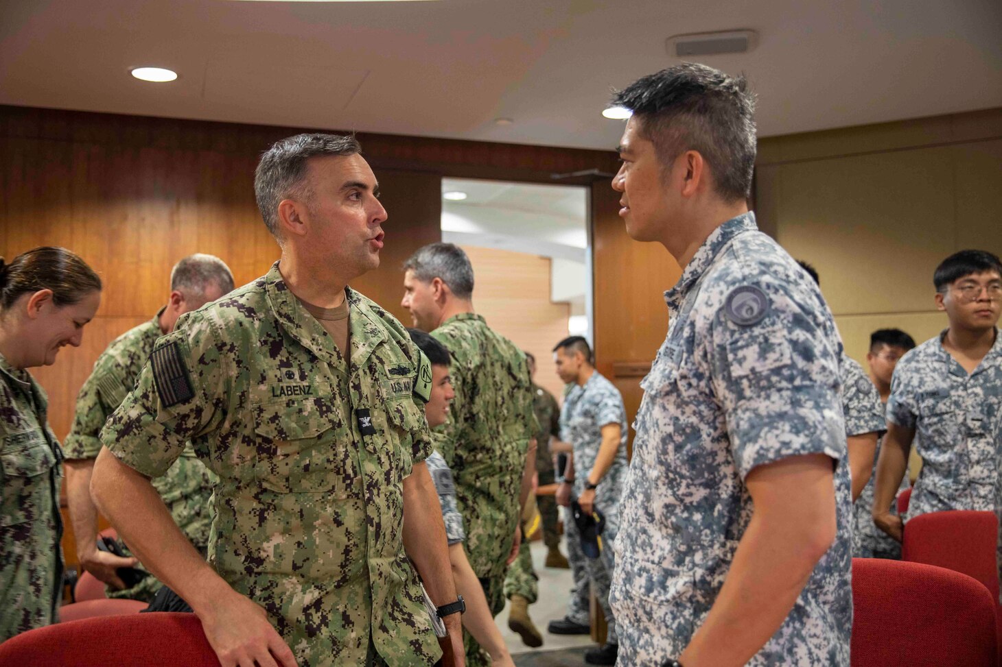 SINGAPORE (Jan. 9, 2023) Capt. Tim LaBenz, Destroyer Squadron 7 commodore, and Republic of Singapore Navy Senior Lt. Col. Daniel Koh, Deputy Commander of 3rd Flotilla, exchange words during the opening ceremony of Cooperation Afloat Readiness and Training (CARAT)/Marine Exercise (MAREX) Singapore 2022, Jan. 9, 2023. CARAT Singapore is a bilateral exercise between Singapore and the United States designed to promote regional security cooperation, maintain and strengthen maritime partnerships, and enhance maritime cooperation. In its 28th, the CARAT series is comprised of multinational exercises, designed to enhance U.S. and partner forces’ abilities to operate together in response to traditional and non-traditional maritime security challenges in the Indo-Pacific region. The Makin Island Amphibious Ready Group, comprised of amphibious assault ship USS Makin Island (LHD 8) and amphibious transport dock USS Anchorage (LPD 23) and USS John P. Murtha (LPD 26), is operating in the U.S. 7th Fleet area of operations with the embarked 13th Marine Expeditionary Unit to enhance interoperability with Allies and partners and serve as a ready-response force to defend peace and maintain stability in the Indo-Pacific region. (U.S. Navy photo by Mass Communication Specialist 3rd Class Kendra Helmbrecht)