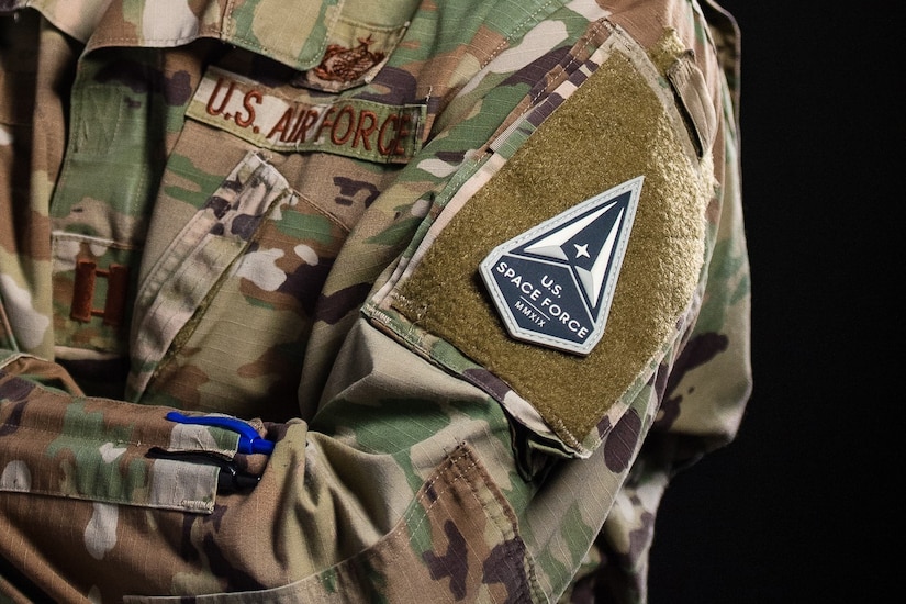 A patch is shown prominently on a camouflage uniform.