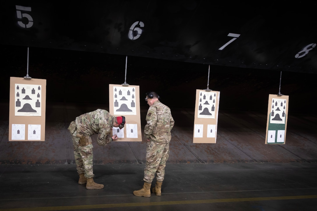 Two service members look closely at target practice charts.
