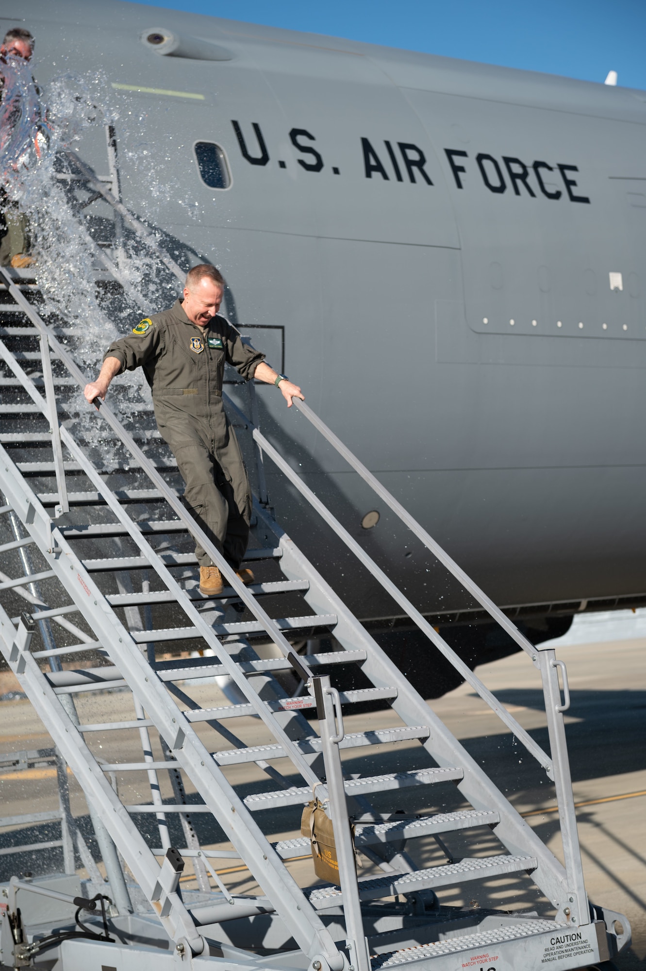 Chief Master Sgt. Tony Parris, 77th Air Refueling Squadron boom operator, exits a KC-46A Pegasus after his fini flight at Seymour Johnson Air Force Base, North Carolina, Jan. 5, 2023. Parris was greeted and hosed down with water and champagne by his family and other service members upon completion of the fini flight. (U.S. Air Force Photo by Airman 1st Class Rebecca Sirimarco-Lang)