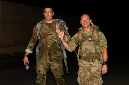 U.S. Army Sgt. Jonathan Licurse, a petroleum supply specialist assigned to Company D, 1st Battalion, 69th Infantry Regiment, and 1st Sgt. Jeffrey Dorvee, the senior enlisted leader of Company D, 1st Battalion, 69th Infantry Regiment, fist-bump during a Norwegian Foot March at Camp Lemonnier, Djibouti, Dec. 16, 2022. Participants were required to ruck 18.6 miles while carrying 25 pounds of dry weight.