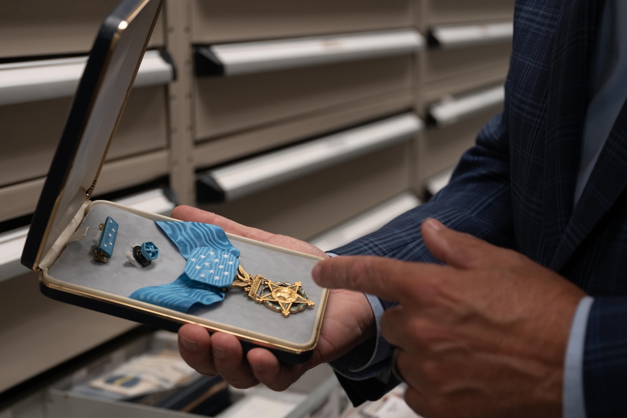 A person holds an open box with a Medal of Honor inside.