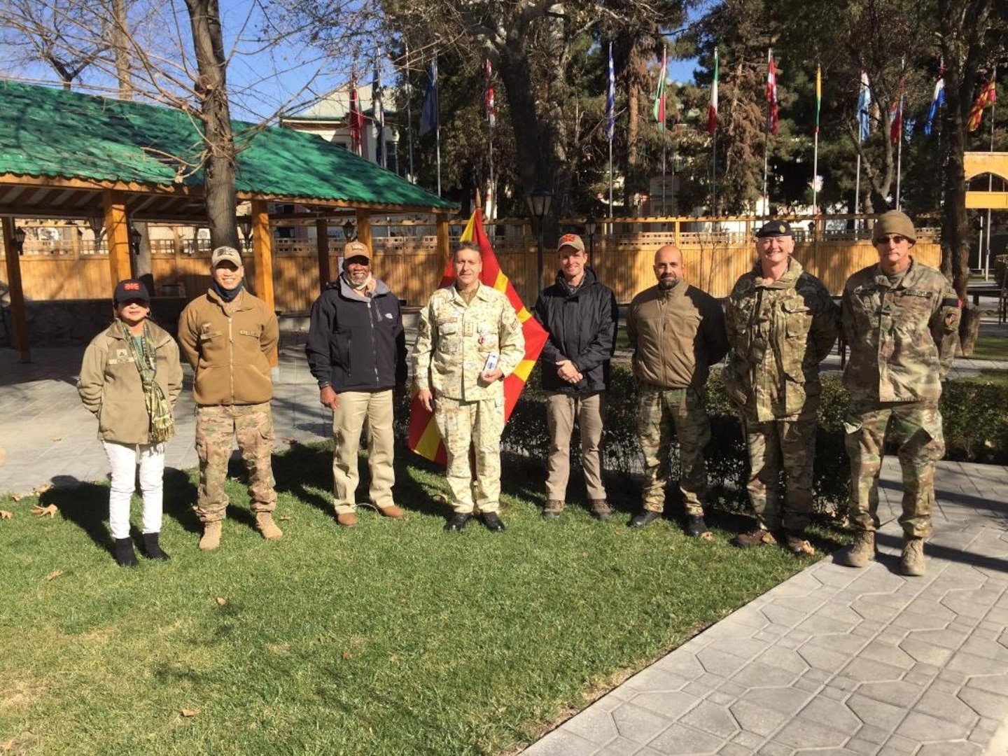 an international group of military members stand on a lawn