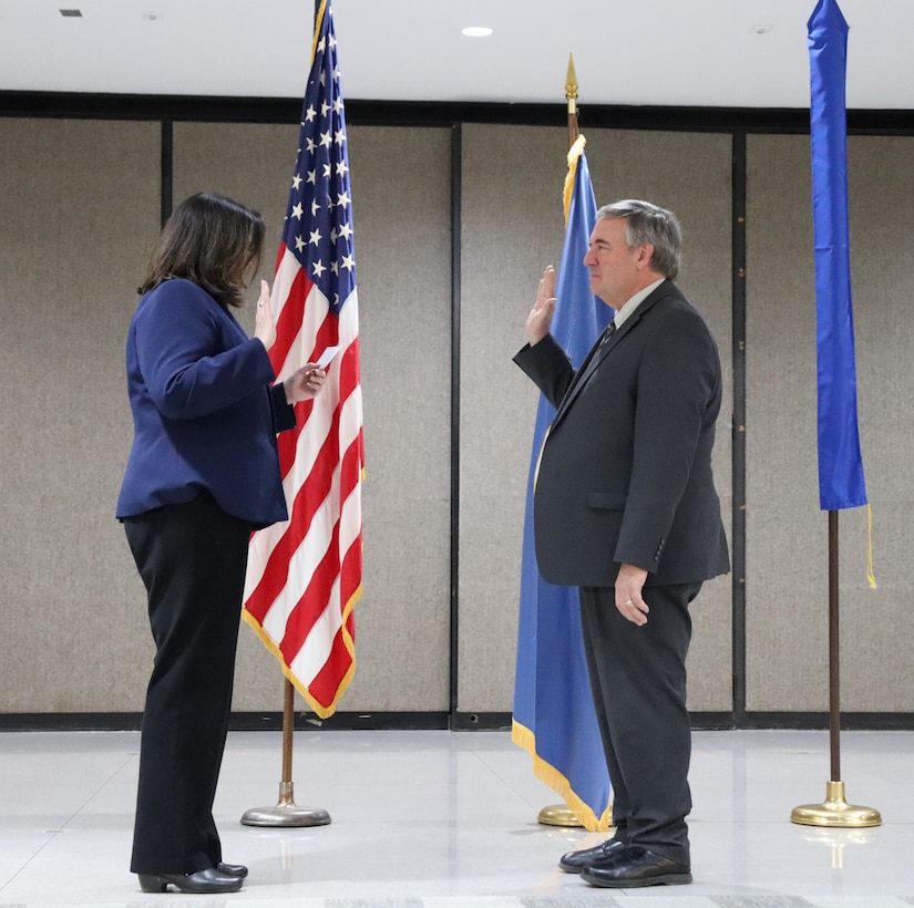 man and woman in business attire with flags behind them