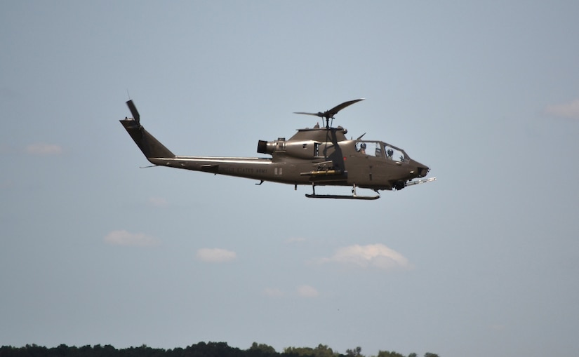 A helicopter flies above a tree line.