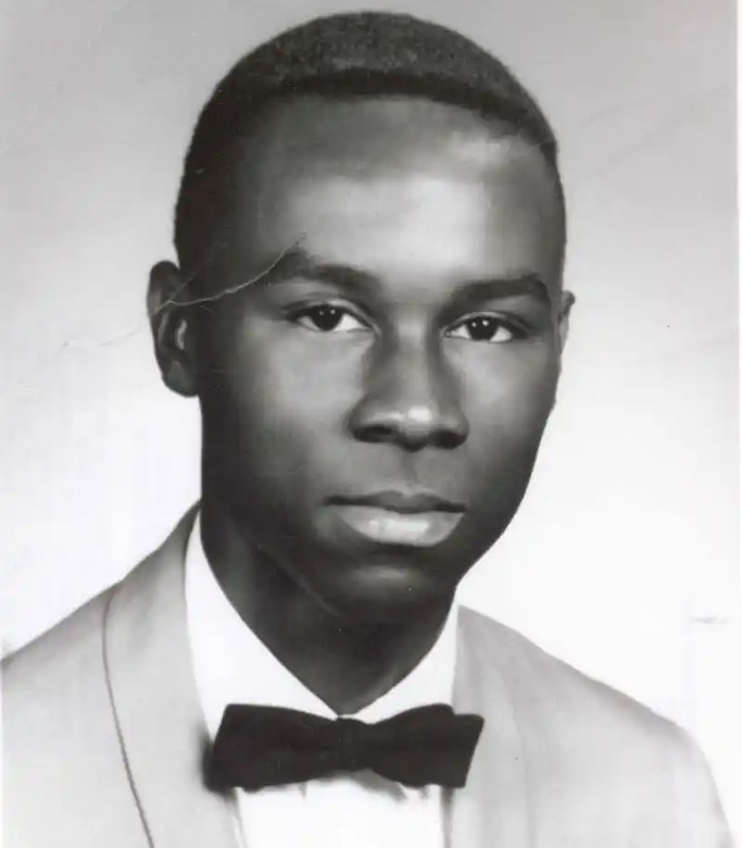 A man in a suit and bowtie poses for a photo.