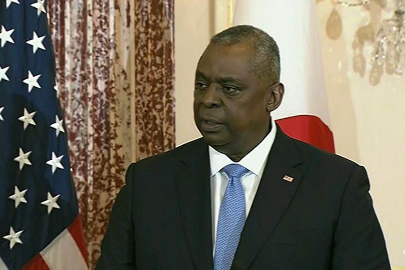 Bust shot of Secretary of Defense Lloyd J. Austin III with the American and Japanese flags in the background.