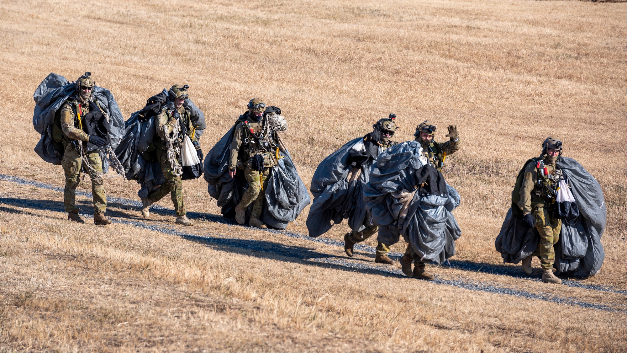 Six US army paratroopers carry their gear back to a prep area