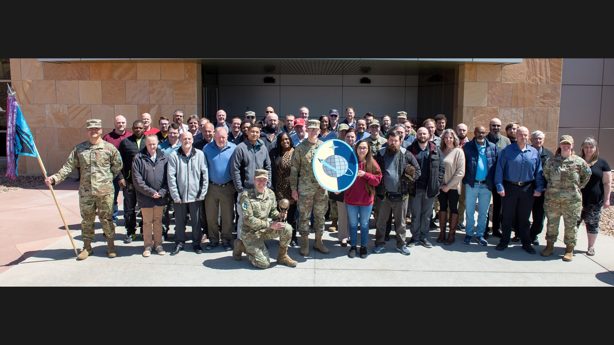 Members of the 12th Delta Operations Squadron stand for a group photo. In the front, a member holds a bronze time capsule created out of their squadron symbol – the iconic hoisted globe above Atlas’ shoulders. (Courtesy photo)