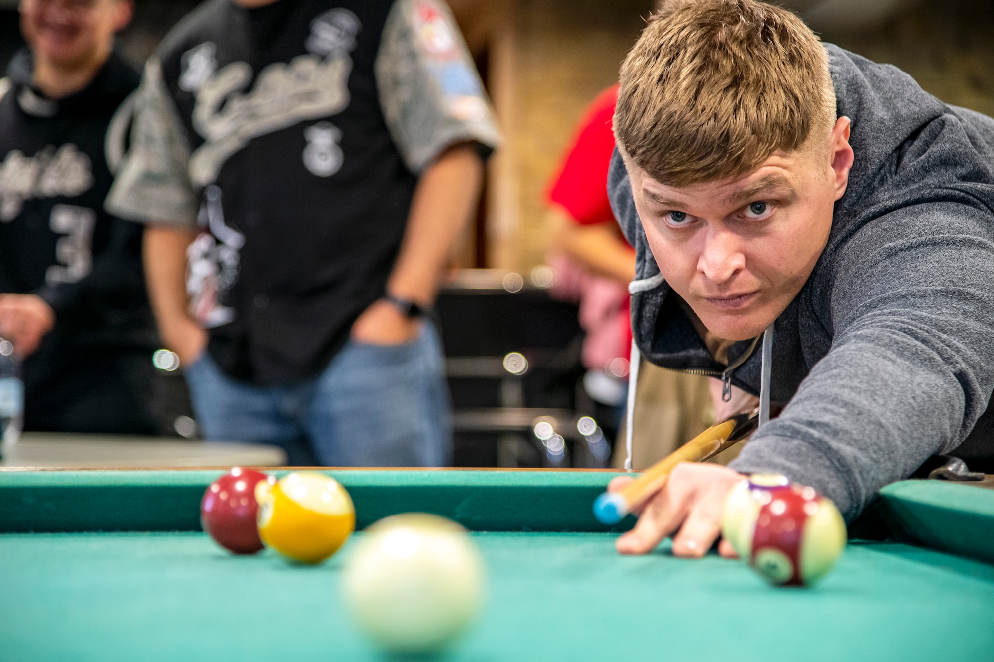 An Airman from the 501st Combat Support Wing lines up a shot during a game of billiards at RAF Croughton, England, Jan. 6, 2022. Airmen from RAF Croughton, RAF Welford and RAF Fairford came together to interact and compete at various games and activities to build camaraderie and togetherness. (U.S. Air Force Photo by Staff Sgt. Eugene Oliver)