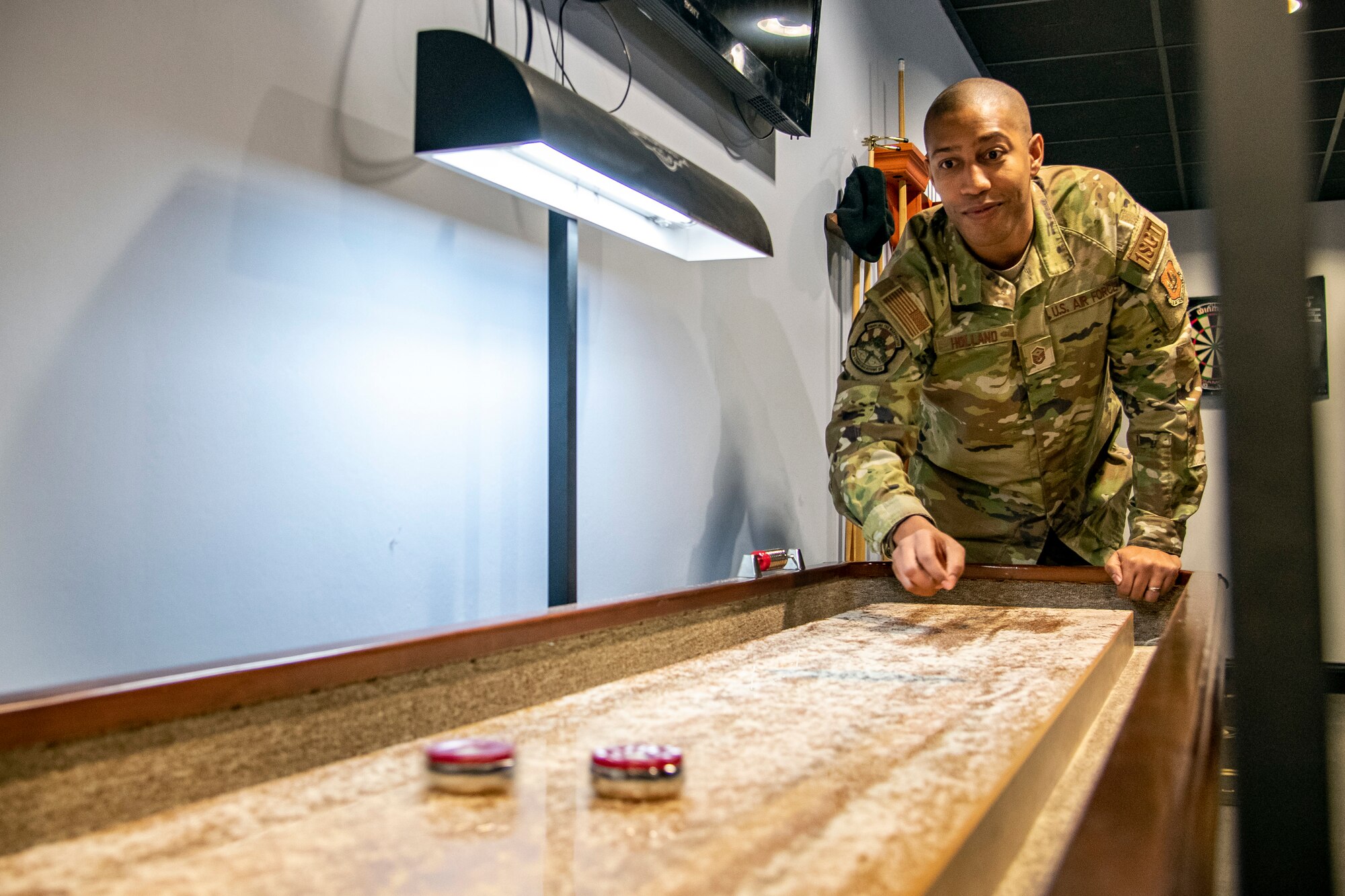 U.S. Air Force Master Sgt. Lamont Holland, 422d Communications Squadron first sergeant, plays a game of shuffleboard during the Crown Olympics at RAF Croughton, England, Jan. 6, 2022. Airmen from RAF Croughton, RAF Welford and RAF Fairford came together to interact and compete at various games and activities to build camaraderie and togetherness. (U.S. Air Force Photo by Staff Sgt. Eugene Oliver)