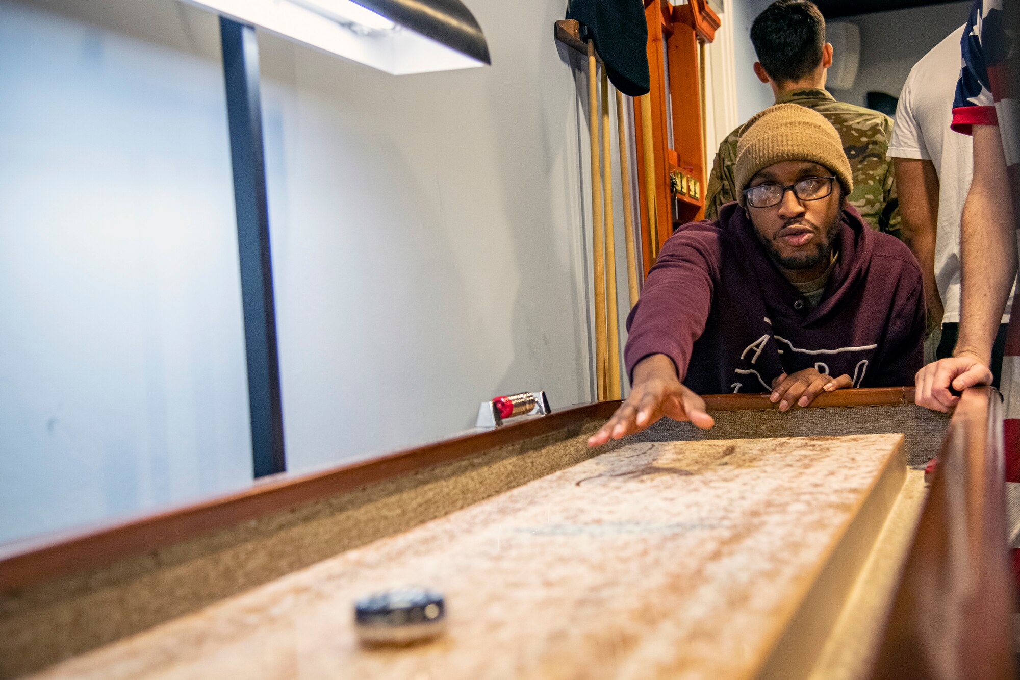 An Airman from the 501st Combat Support Wing, plays a game of shuffleboard during the Crown Olympics at RAF Croughton, England, Jan. 6, 2022. Airmen from RAF Croughton, RAF Welford and RAF Fairford came together to interact and compete at various games and activities to build camaraderie and togetherness. (U.S. Air Force Photo by Staff Sgt. Eugene Oliver)