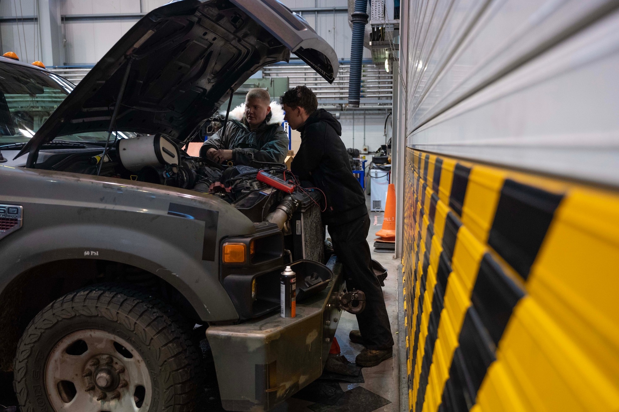 Airmen from the 100th Logistics Readiness Squadron vehicle management section troubleshoot an engine startup on a government vehicle at RAF Mildenhall, England, Jan. 9, 2023. Flightline vehicle maintenance Airmen repair and service a wide range of vehicles, to include: global aircraft deicer trucks, Caterpillar 50K forklifts, Tunner 60K aircraft cargo loader/transporters and Grove pushback tow tractor MB-2. (U.S. Air Force photo by Airman 1st Class Viviam Chiu)
