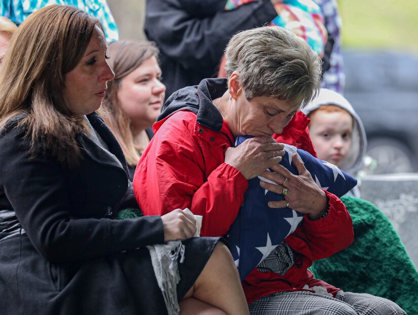 Ms. Pauletta Willard hugs the flag while being comforted by family at Grove Hill Cemetery in Shelbyville, Ky. on Dec. 9, 2022. Willard's mother, retired Master Sgt. Wilma J. Ross was honored by the Kentucky Army National Guard color guard during Ross's funeral. (Army National Guard photo by Sgt. 1st Class Benjamin Crane)