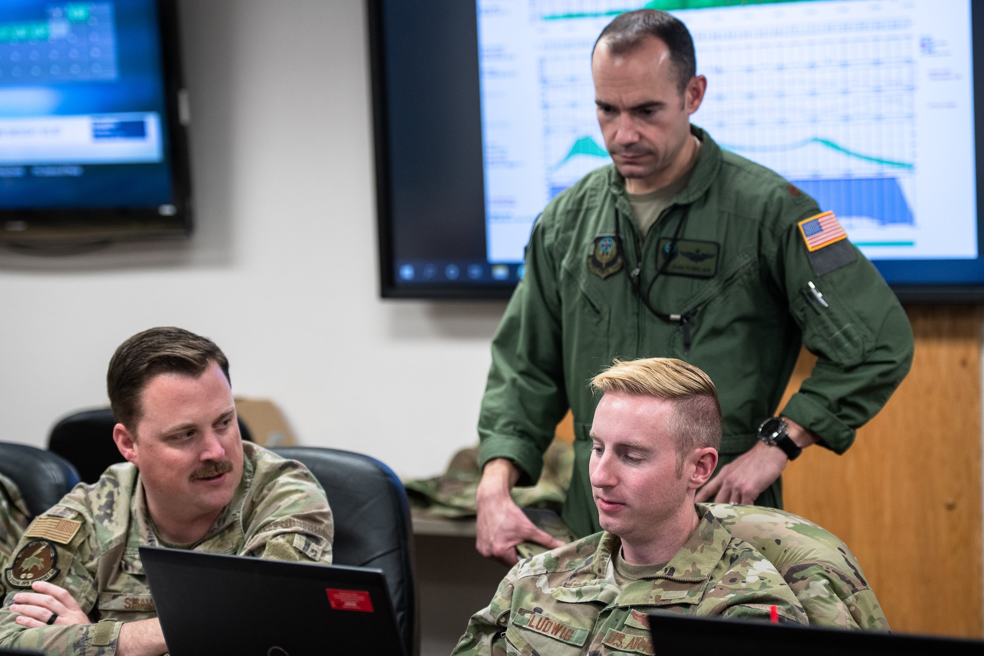 airmen sit at a computer and review mission plans