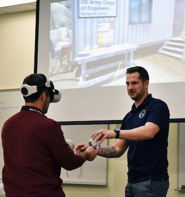 Kyle Shireman, Huntsville Center safety manager and visionary behind the Center’s new USACE Safety Trainer 360, explains how to use the virtual reality construction safety game’s headset and controllers to Shane Henry, audit technician, during a Occupational Safety and Health Administration 10-Hour Training Course held at the U.S. Army Engineering and Support Center, Huntsville. (Photo by Kristen Bergeson)