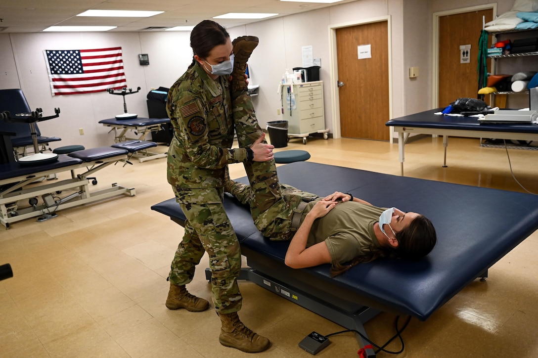 An airman performs physical therapy on a fellow service member.