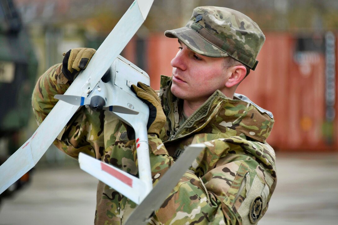 A soldier works on a small unmanned aircraft system.