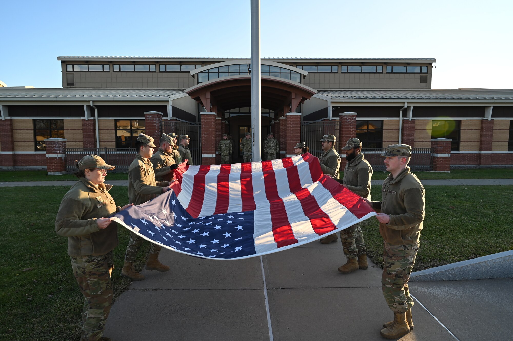 Members of the 174th Attack Wing lower and fold the flag during a retreat ceremony at the end of drill weekend at Hancock Field Air National Guard Base, January 9, 2023.