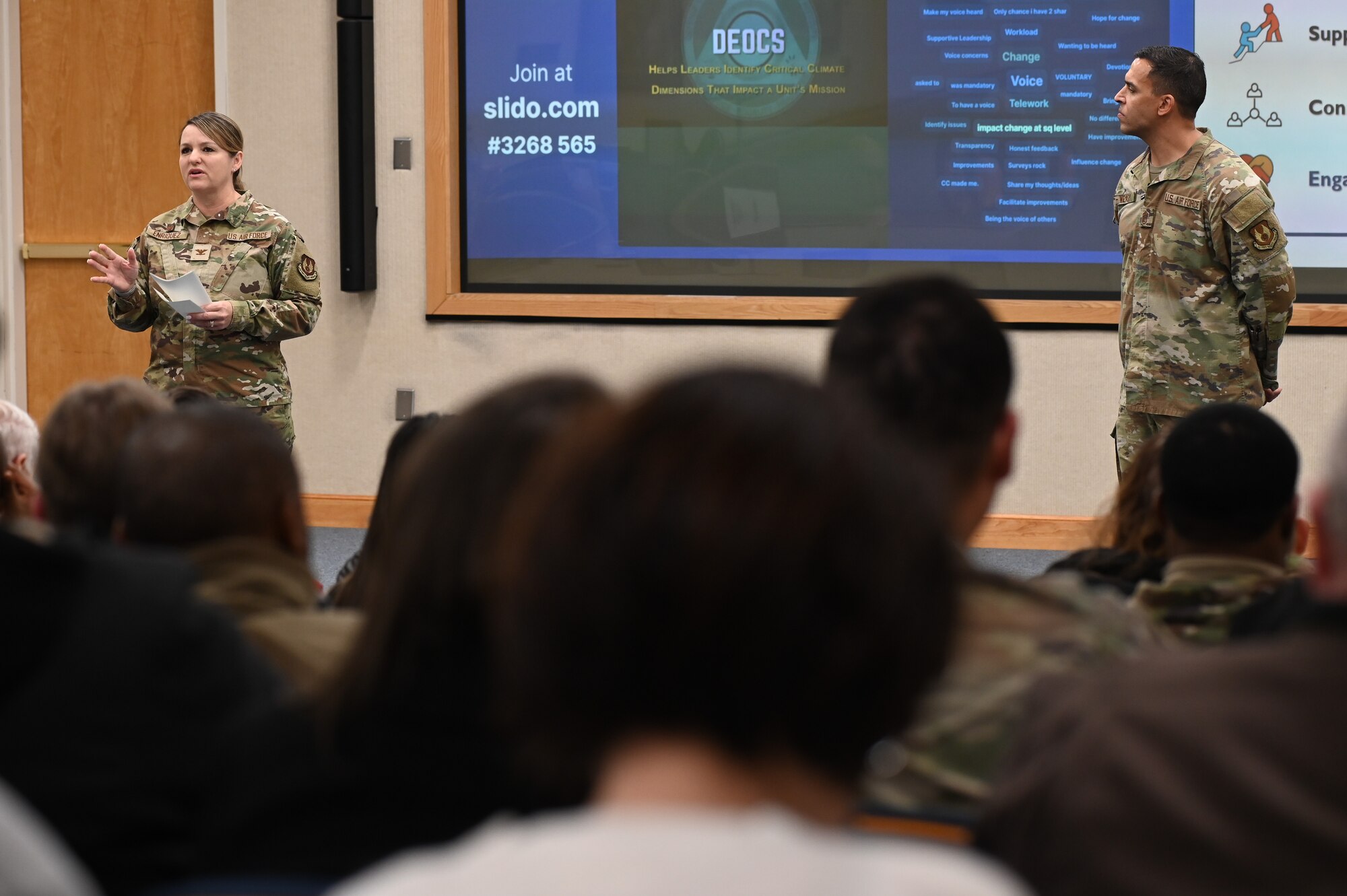 Col. Taona Enriquez, 66th Air Base Group commander, speaks to members of the workforce during a commander’s call at Hanscom Air Force Base, Mass., Jan. 11., while Chief Master Sgt. Alan Weary, 66 ABG command chief, looks on. The command team introduced the Strategic Plan and lines of effort, highlighted command- and center-level award winners, updated personnel about ongoing initiatives and more during the quarterly session. (U.S. Air Force photo by Todd Maki)