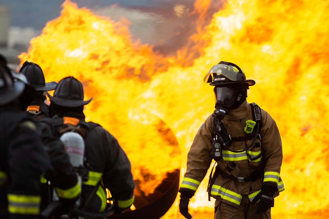 Firemen line up to work on putting out roaring flames.