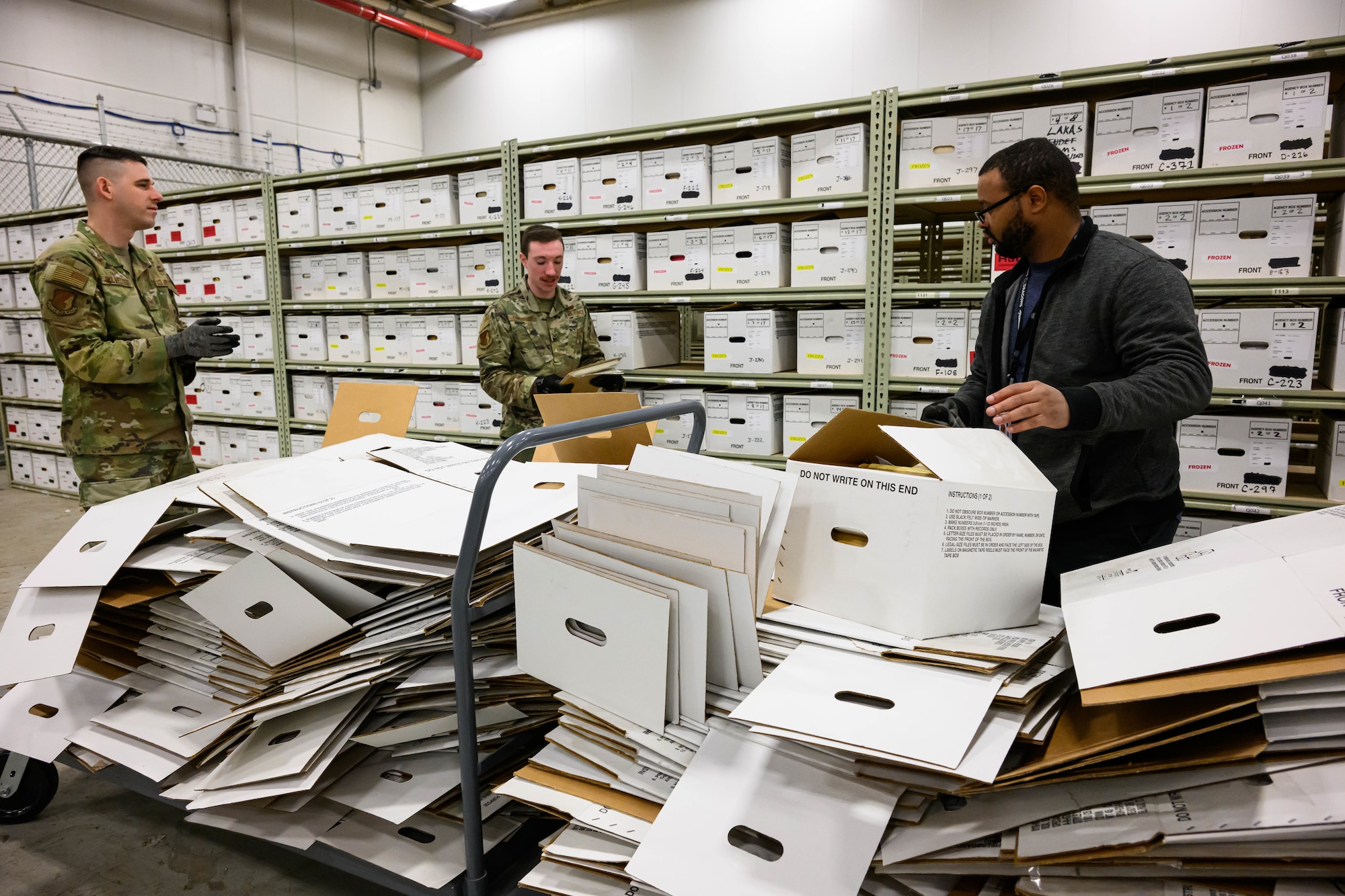 Left to right, Staff Sgt. Jared Sylvester, Senior Airman Brandon Tankersley and Bryce Terry, 75th Communications and Information Directorate, process boxed records at the Records Staging Facility at Hill Air Force Base, Utah, Dec. 22, 2022.  The Office of Management and Budget directed the Air Force to close all agency operated paper storage facilities and transfer permanent and long-retention records to Federal Records Centers operated by the National Archives and Records Administration by Dec. 31, 2022. The staging facility at Hill provided supported to more than 100 organizations. (U.S. Air Force photo by R. Nial Bradshaw)