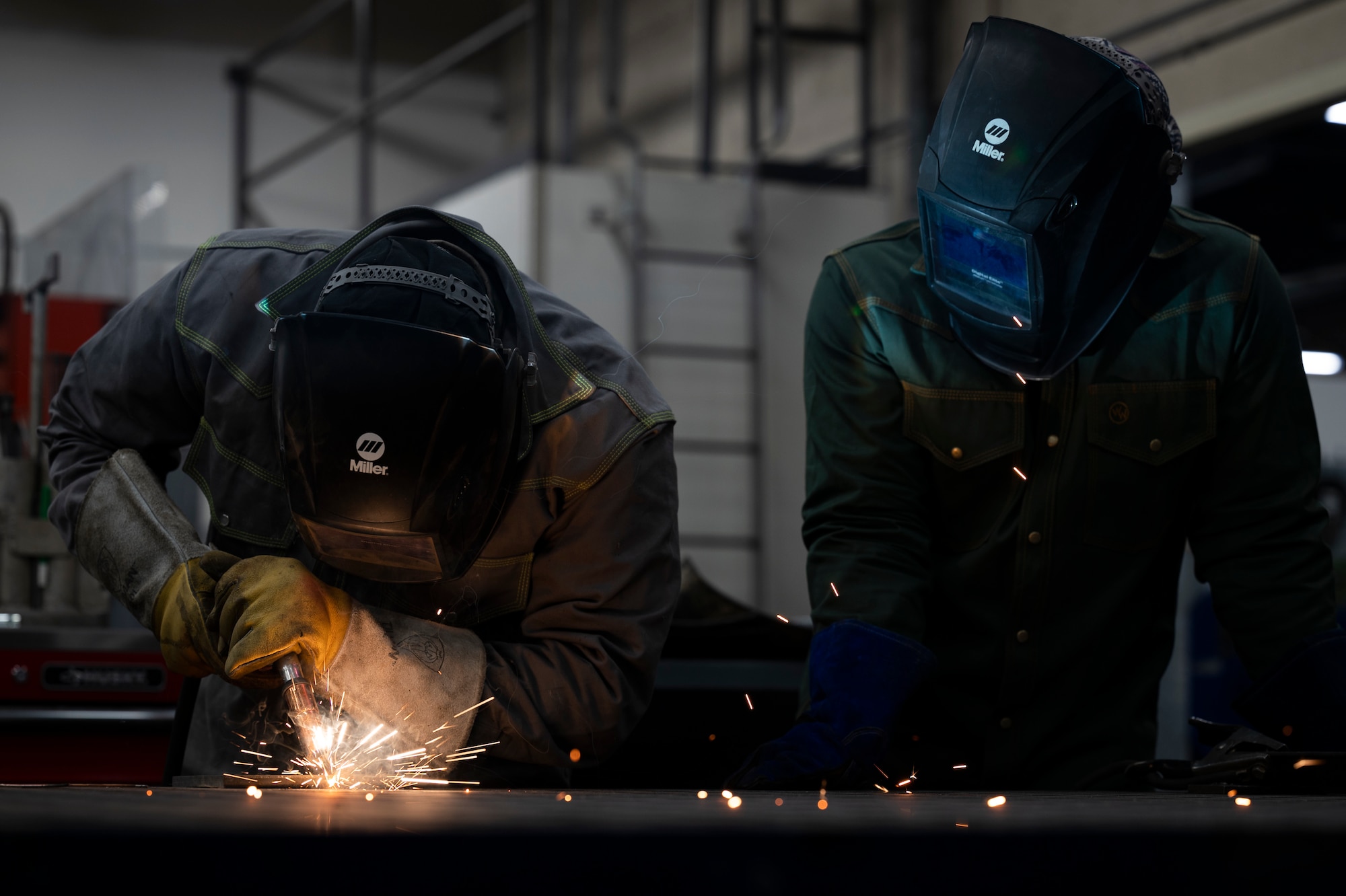 Sparks fly from a metallic inert gas welder as an Airman welds two metal sheets together.