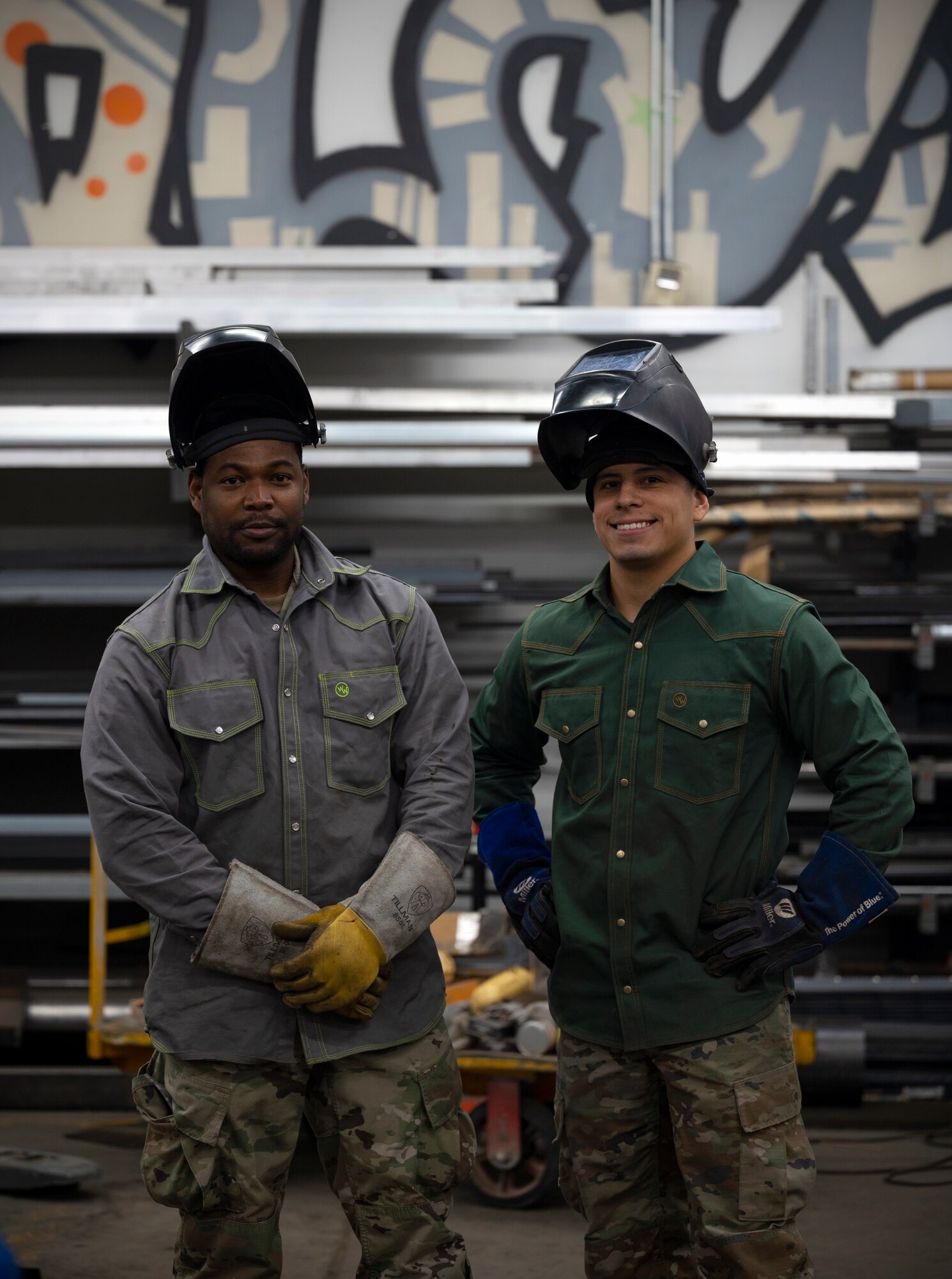 Two men pose with welding masks atop their heads for a photo.