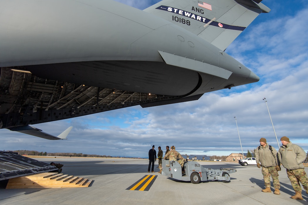Photo of Airmen from the Vermont Air National Guard's 158th Aircraft Maintenance Squadron, along with Airmen from the New York ANG's 105th Airlift Wing, Stewart Air National Guard Base in Newburgh, New York, position wooden ramps to assist with loading equipment onto a C-17 Globemaster III aircraft at the Vermont Air National Guard Base, South Burlington, Vermont, Dec. 4, 2022.
