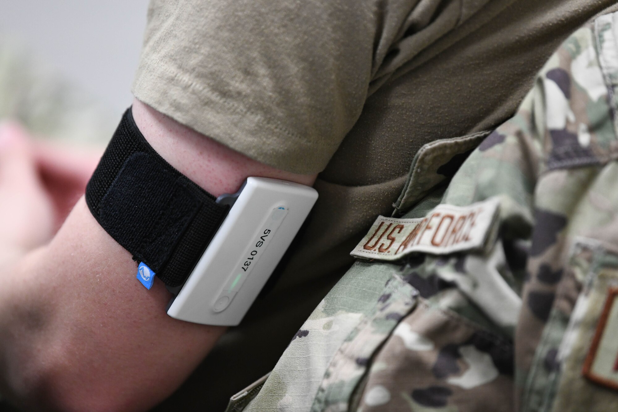 A person wears an black and white medical device around their arm.