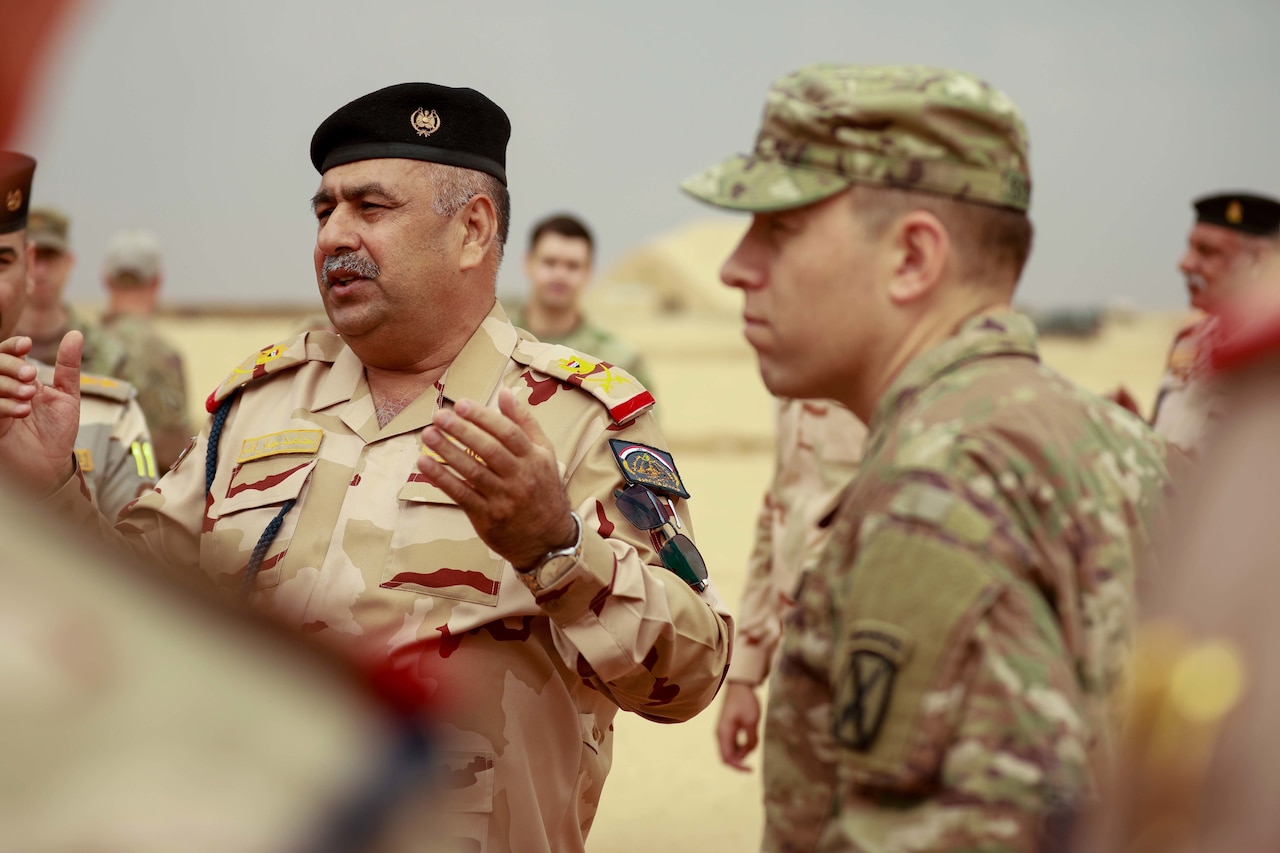 Uniformed military personnel stand near each other.