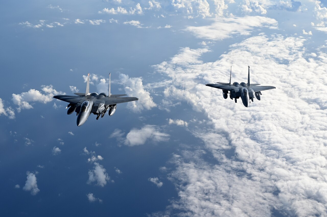 Two U.S. Air Force F-15E Strike Eagles fly next to each other above the clouds.