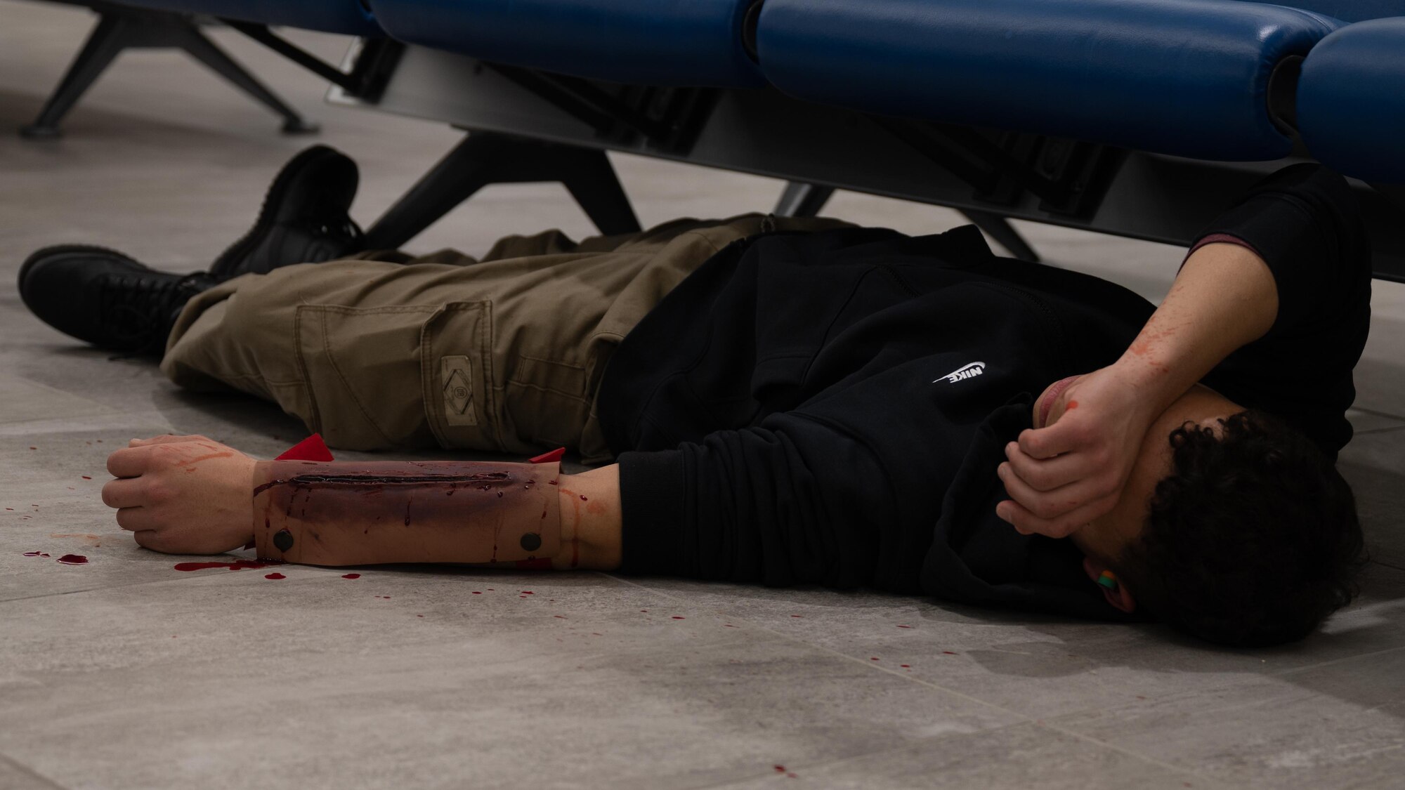 A simulated victim with injuries lays on the floor.