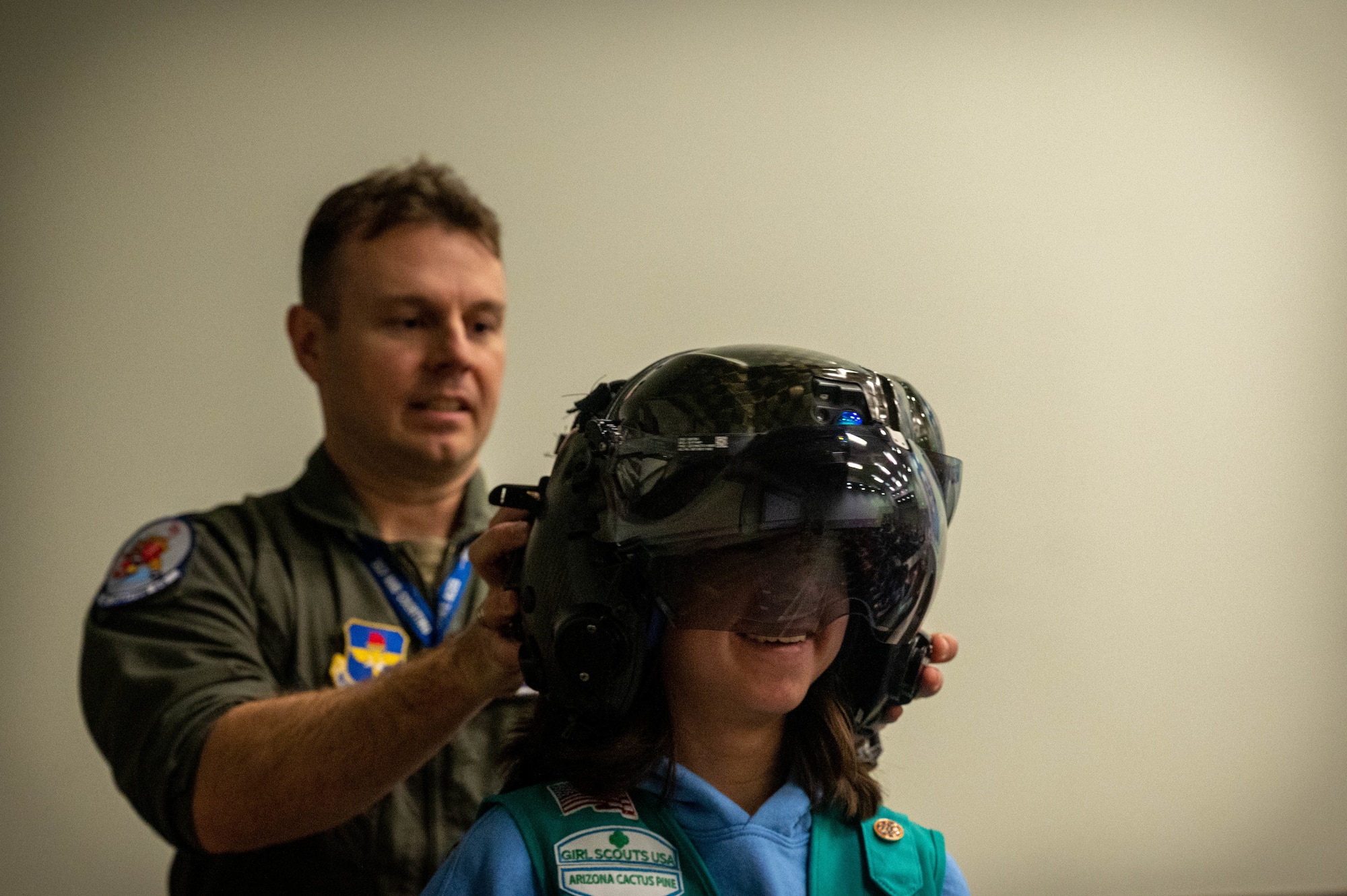 U.S. Air Force Lt. Col. Tyler Smith, 62nd Fighter Squadron commander, fits an F-35A Lightning II helmet onto a Girl Scout Jan. 11, 2023, at Luke Air Force Base, Arizona.