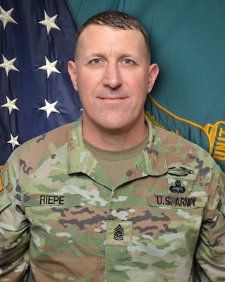 man wearing u.s. army uniform standing in front of flags