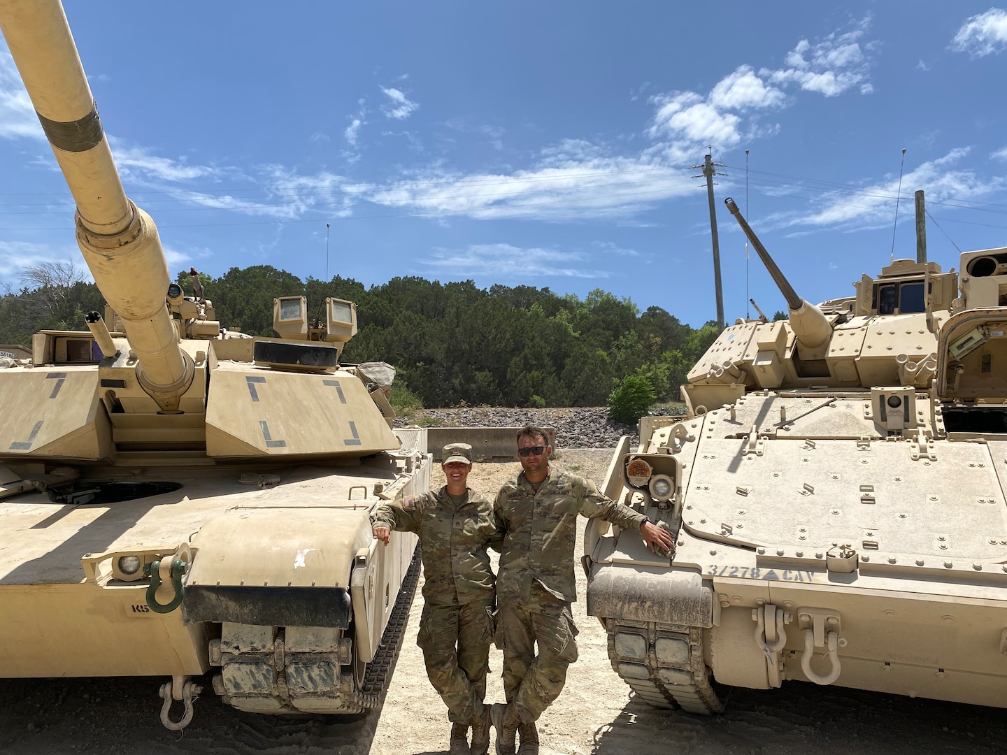 Texas National Guard members Staff Sgt. Elizabeth Cox, left, an M1 Abrams master gunner, and her significant other, Sgt. 1st Class Josh Simmons, a Bradley Fighting Vehicle master gunner, next to their respective armor vehicles. Cox recently became the first female in the Army National Guard to graduate from the Abrams Master Gunner school, an advanced gunnery and maintenance school that earns graduates the designation of Abrams Master Gunner.