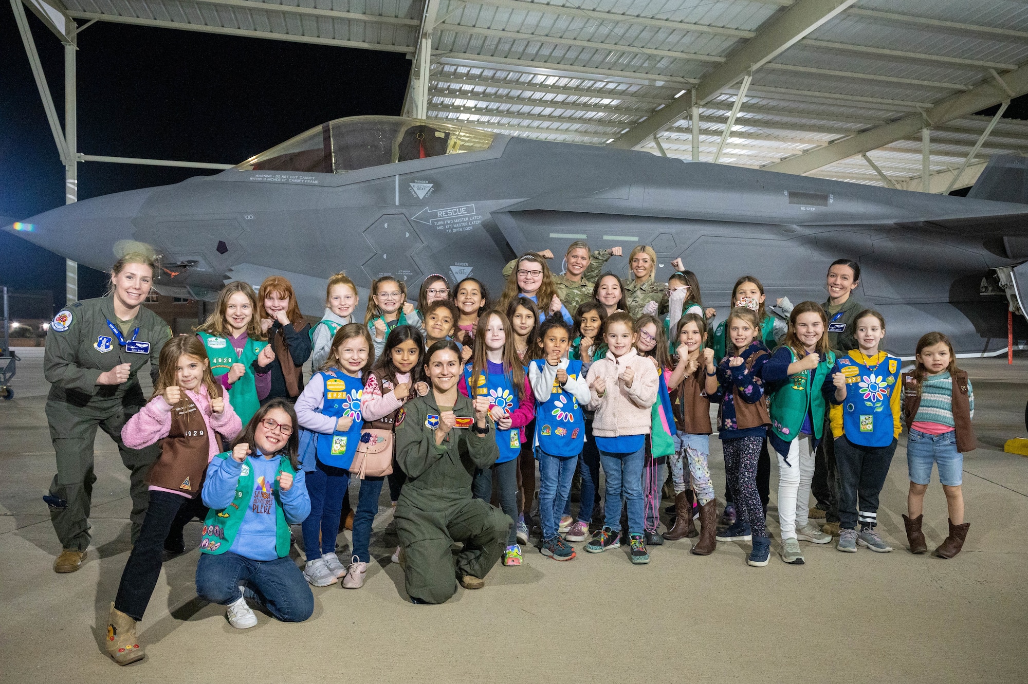 U.S. Air Force Airmen from the 62nd Fighter Squadron and 62nd Aircraft Maintenance Unit, and a local Girl Scouts troop pose for a picture in front of an F-35A Lightning II aircraft Jan. 11, 2023, at Luke Air Force Base, Arizona.