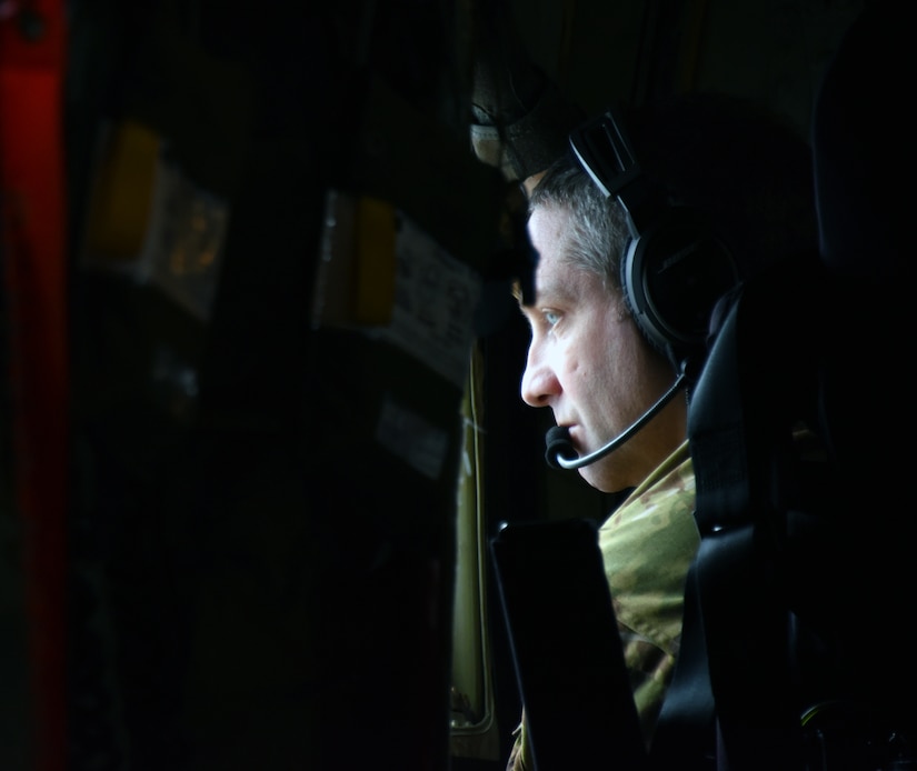 An airman looks out of the window inside of a C-130 J.