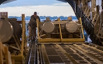 A photo of a man pushing cargo onto a C-17.
